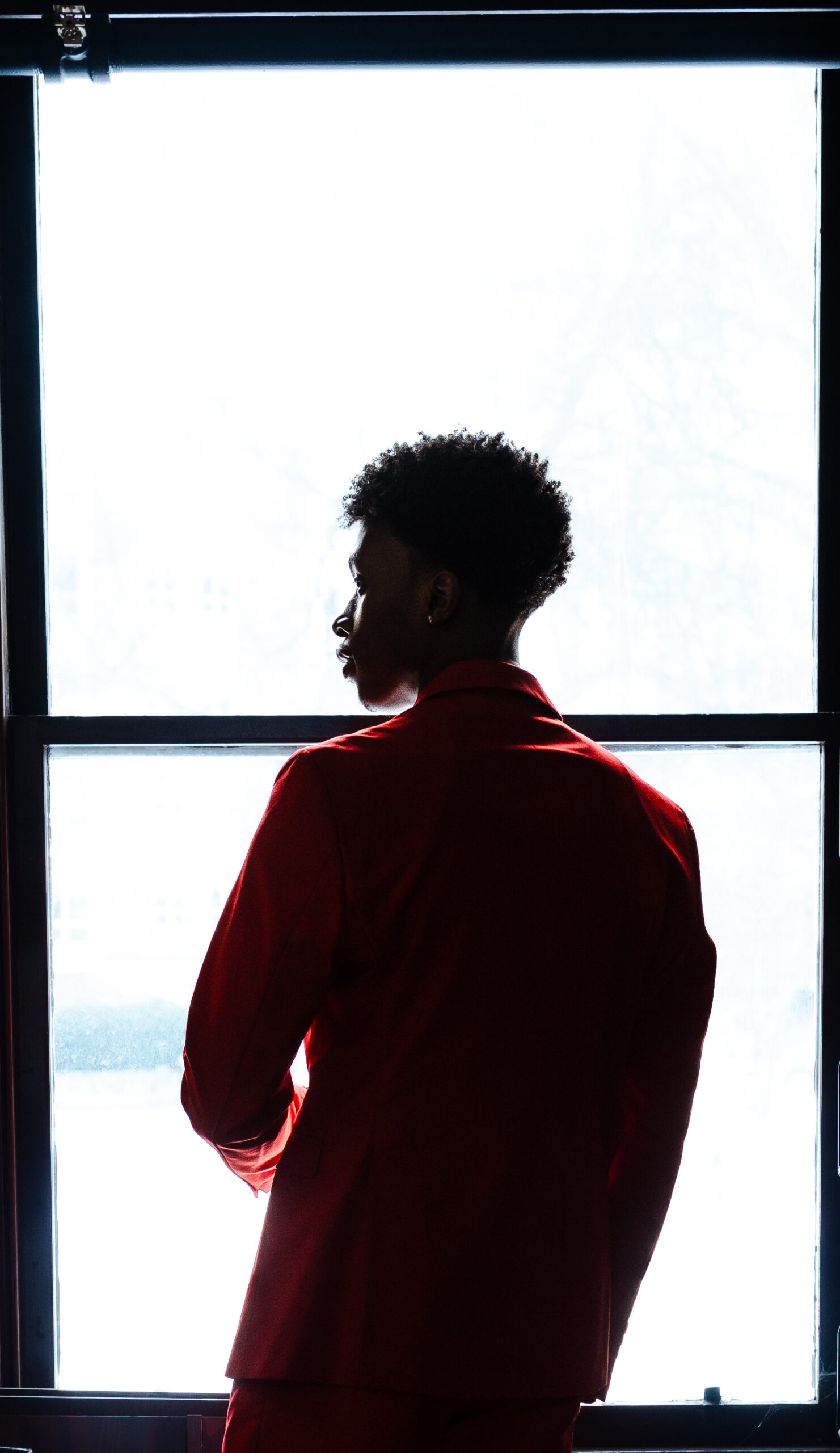 Silhouette of a man in a red suit against a bright window