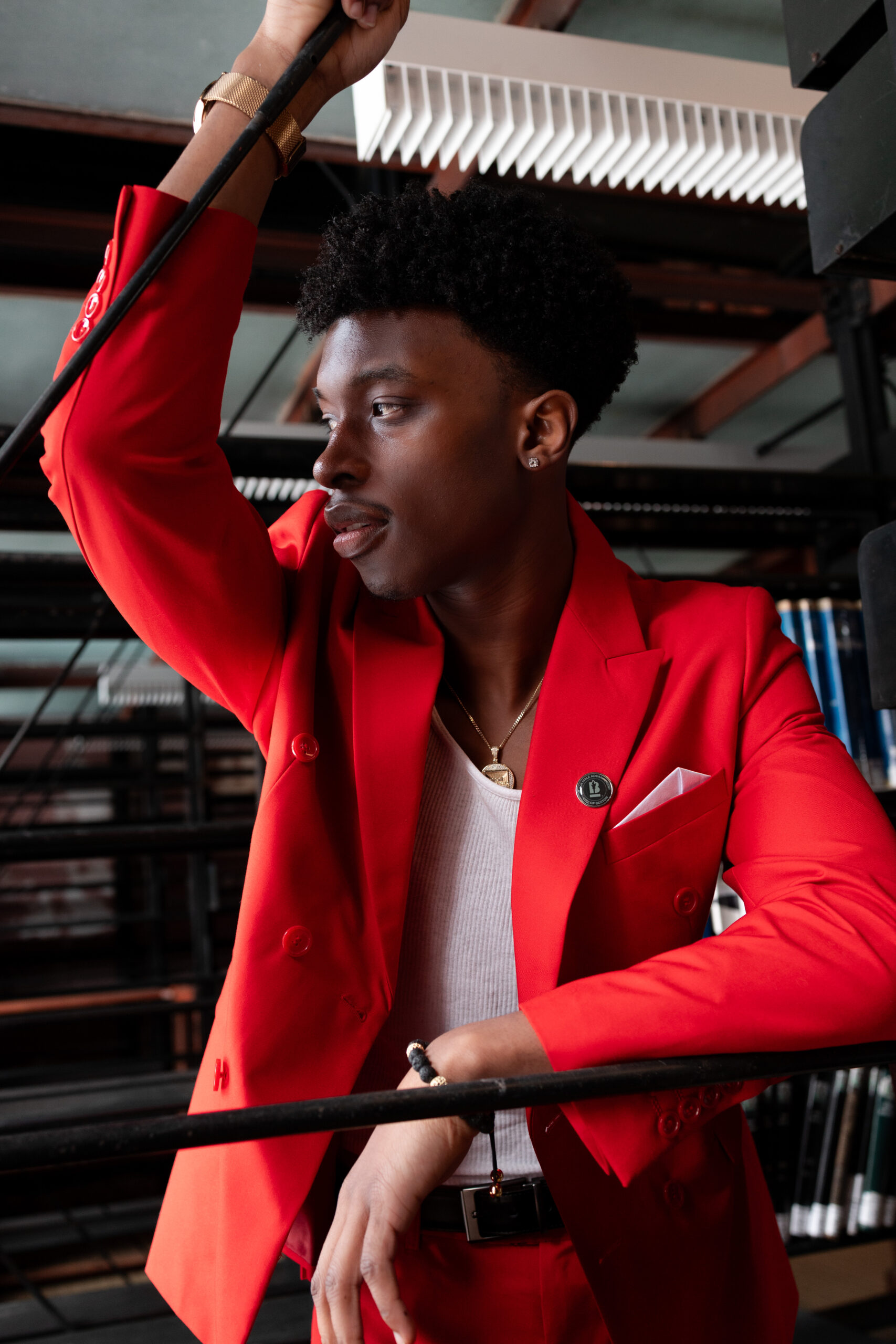 Man in a red suit looking away, framed by library shelving